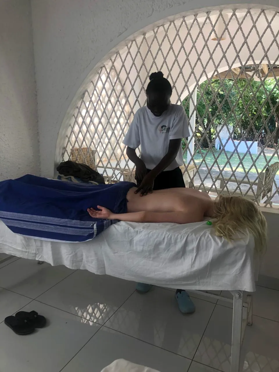 Back massage treatment in a calm shaded room in Diani